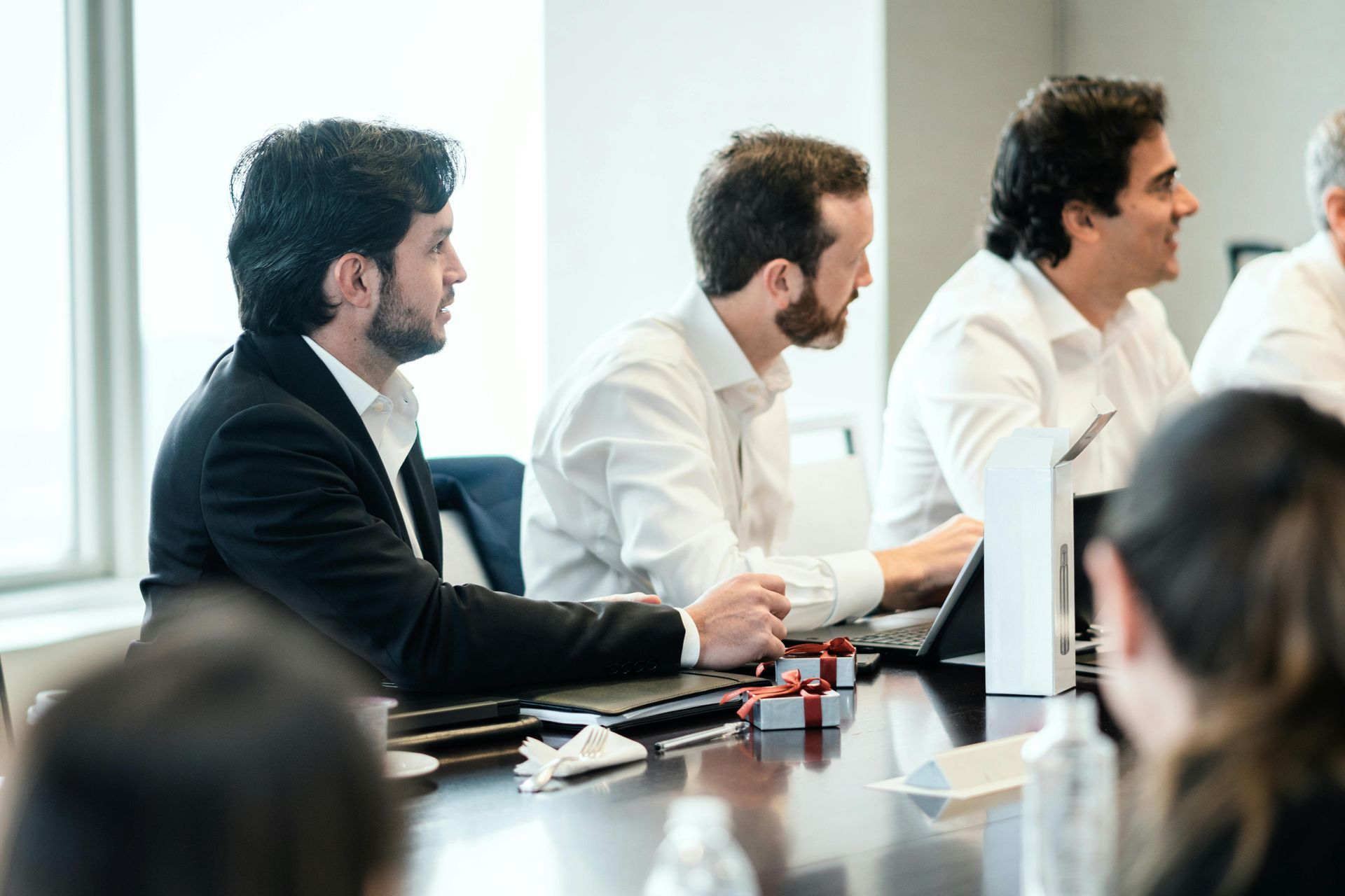 A group of people are sitting around a table in front of a screen that says first choice