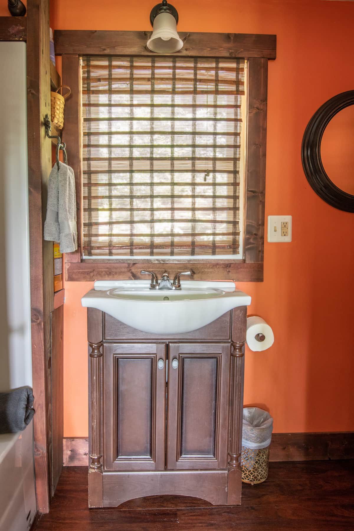 A bathroom with a sink and a window with blinds.