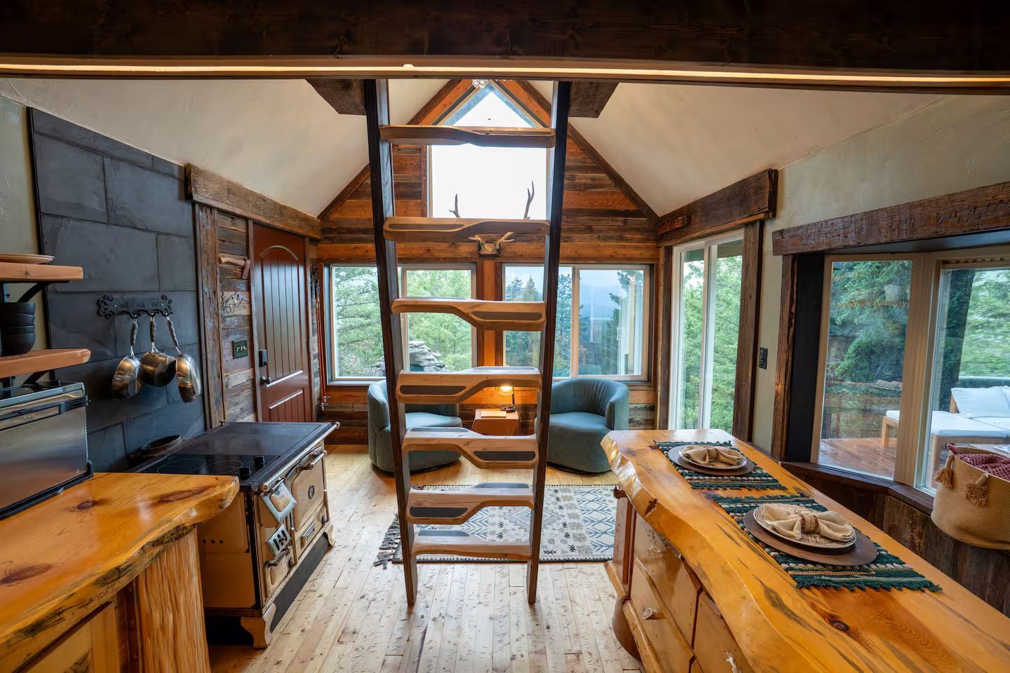 A kitchen in a log cabin with a ladder leading up to the second floor.