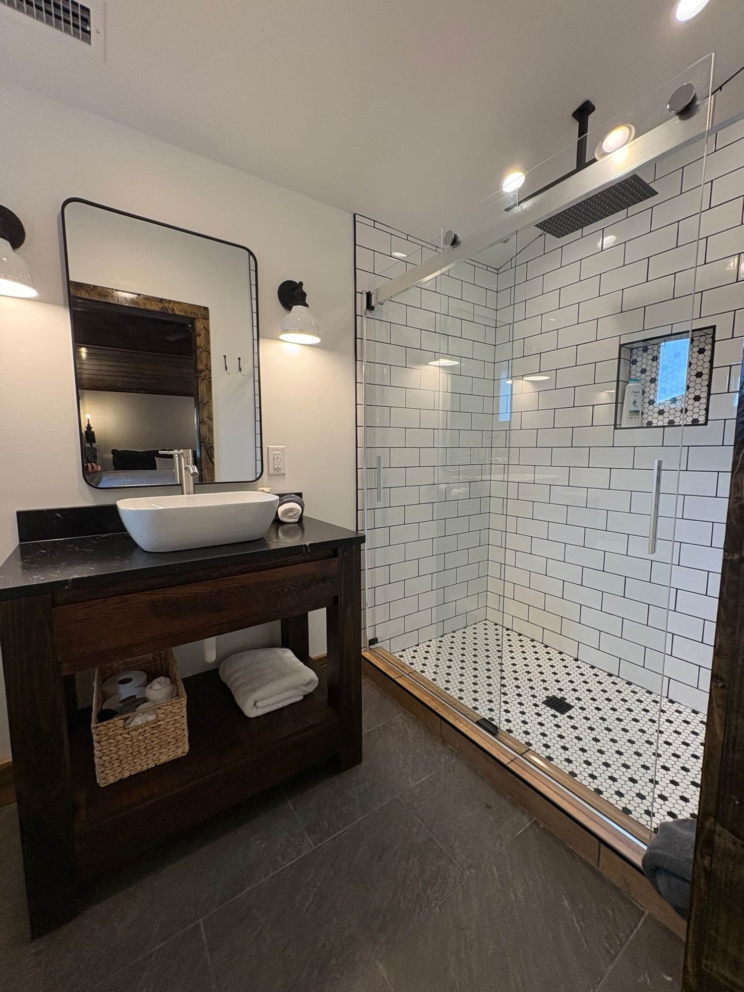 A bathroom with a sink , mirror and walk in shower.