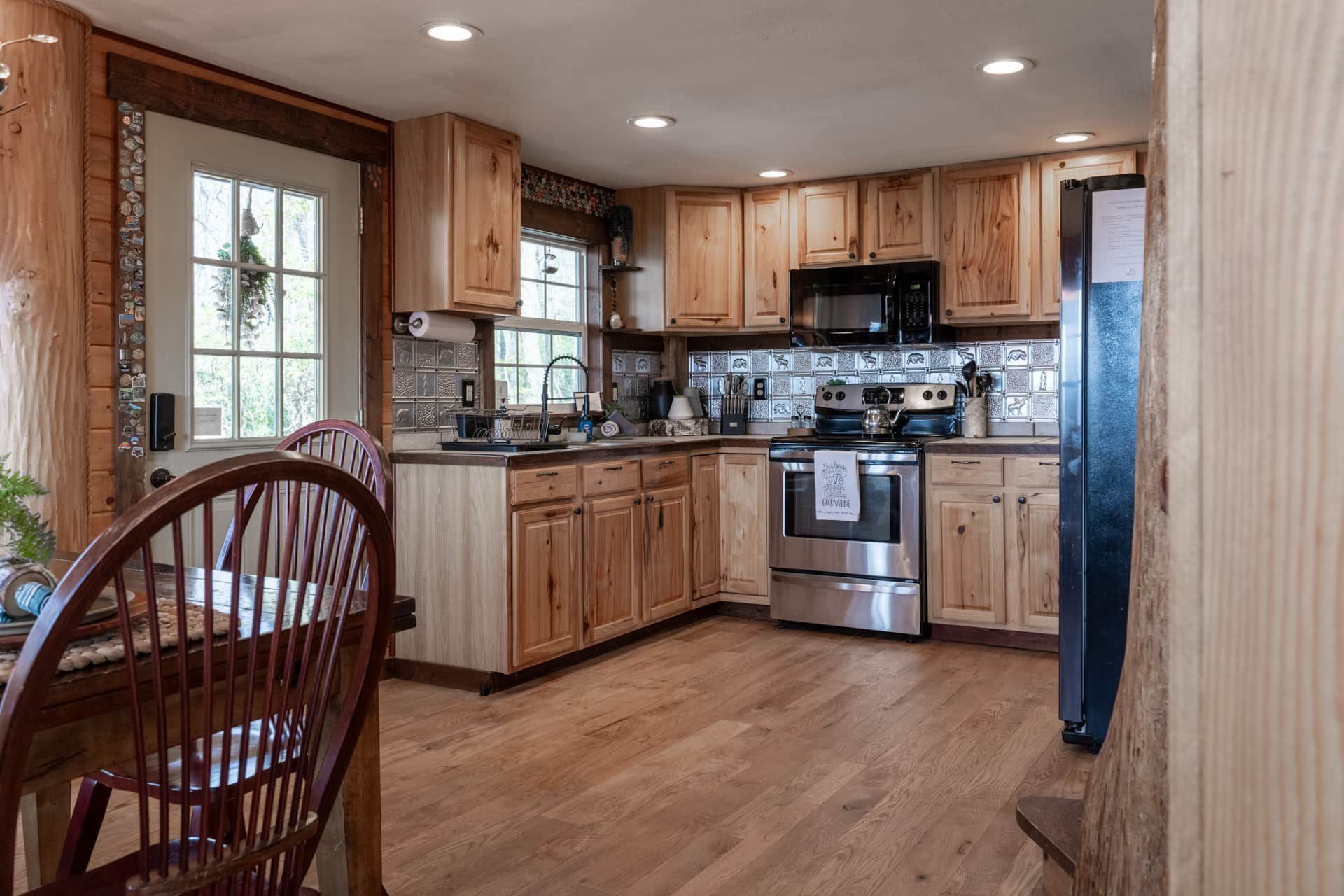 A kitchen with wooden cabinets , stainless steel appliances , a table and chairs.
