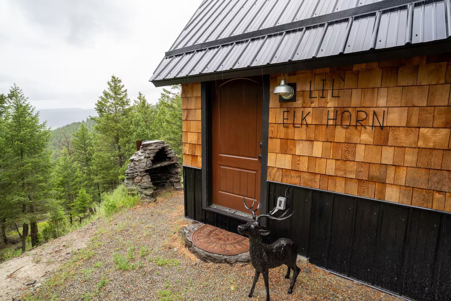 A small cabin with a deer statue in front of it.