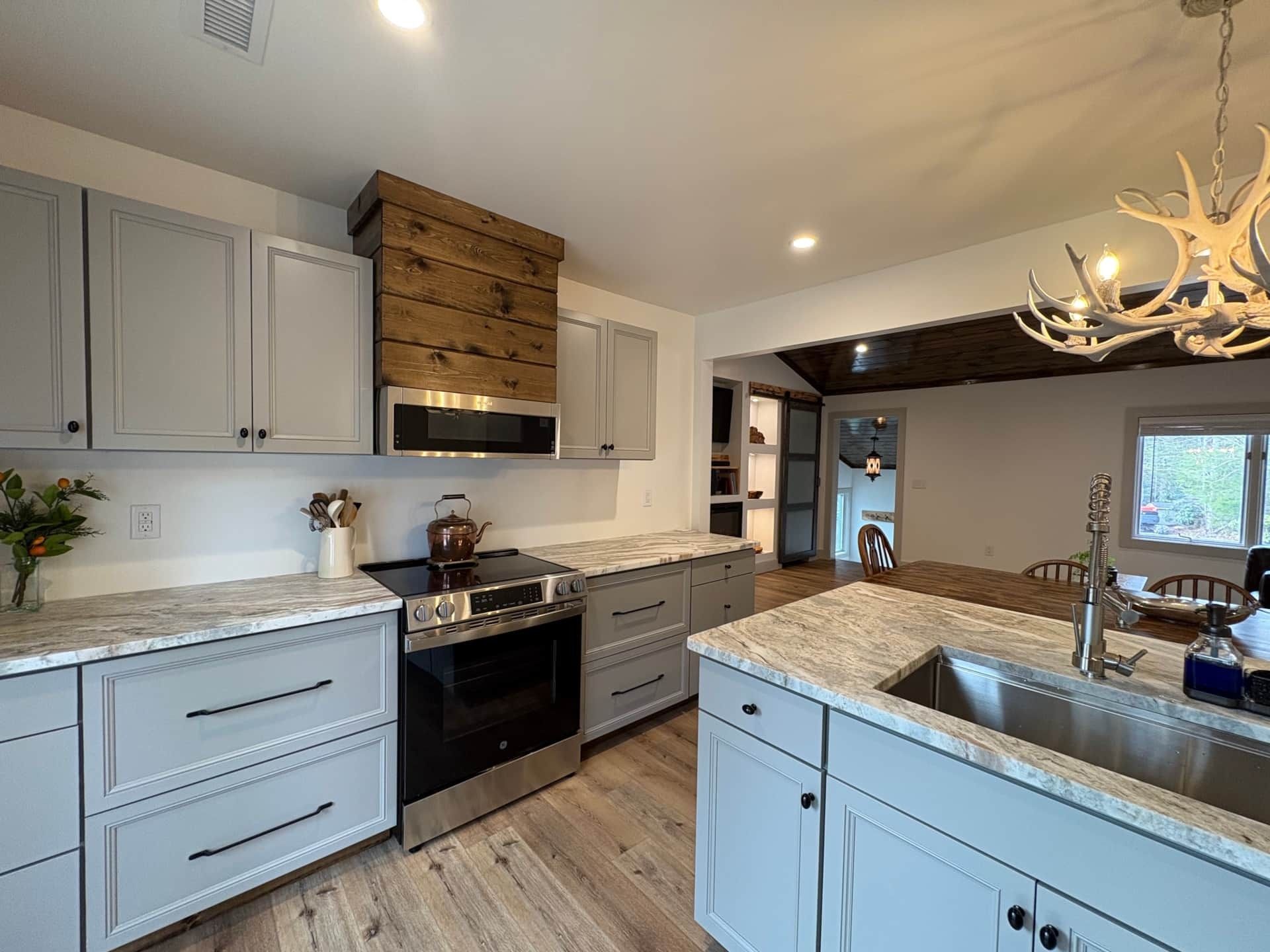 A kitchen with gray cabinets , stainless steel appliances , granite counter tops , and a sink.