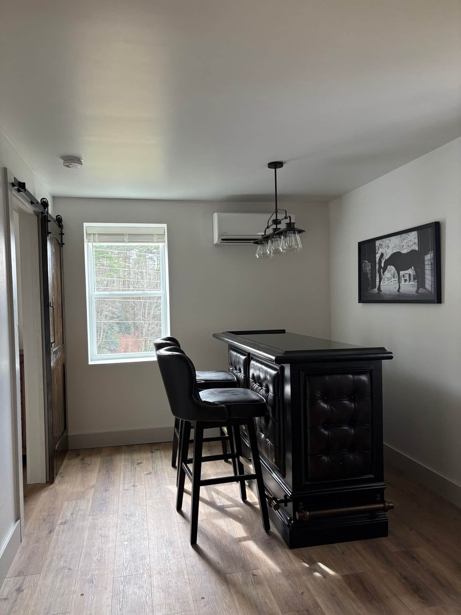 A room with a bar and chairs in it and a window.