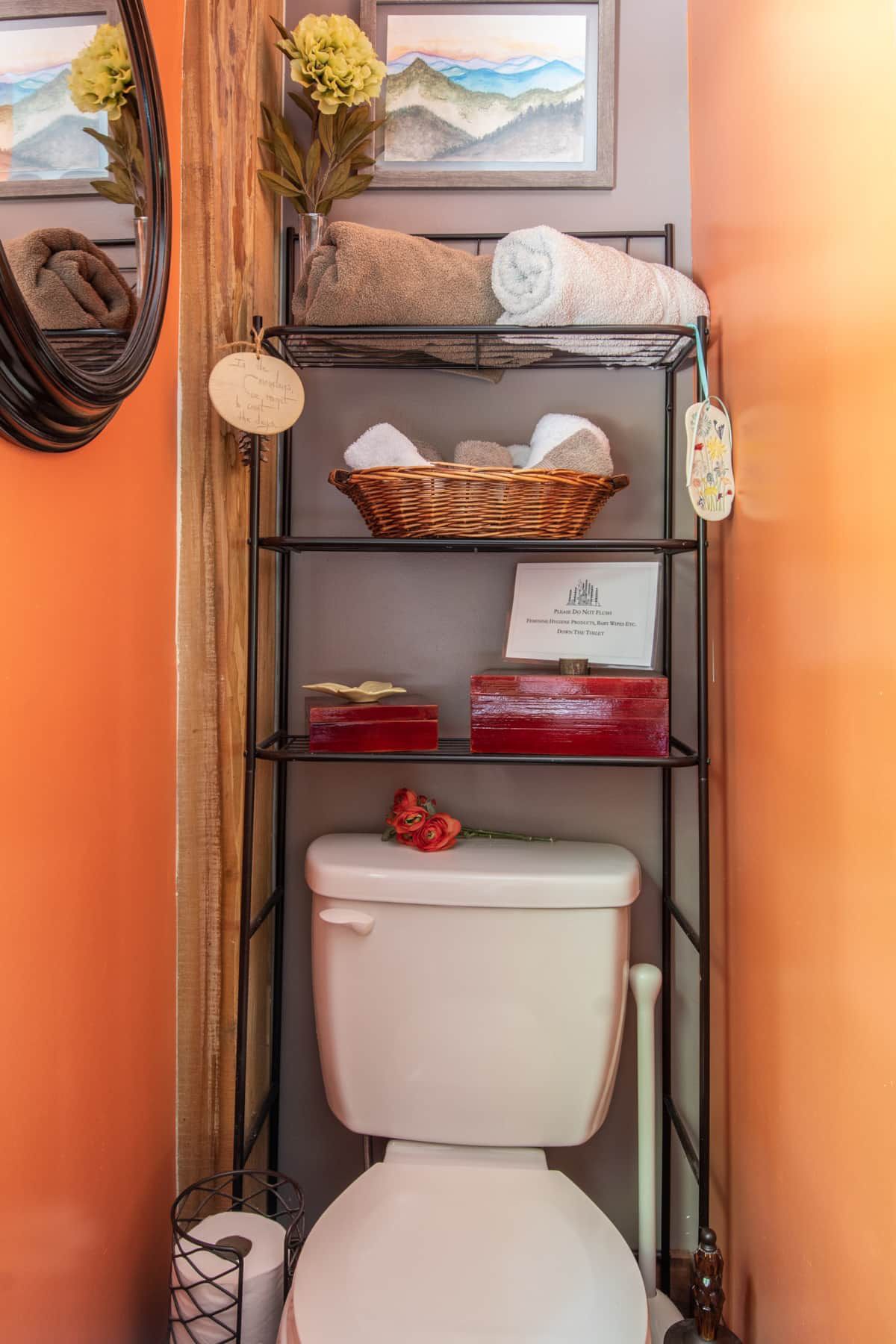 A bathroom with a toilet and a shelf with towels on it.