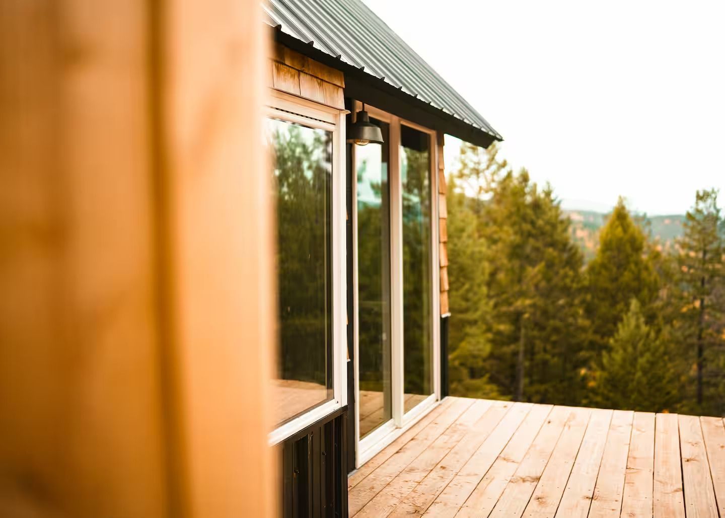 A wooden house with a deck and a view of the woods.