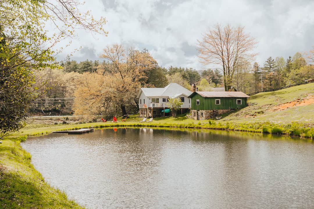 A house is sitting on the shore of a lake surrounded by trees.