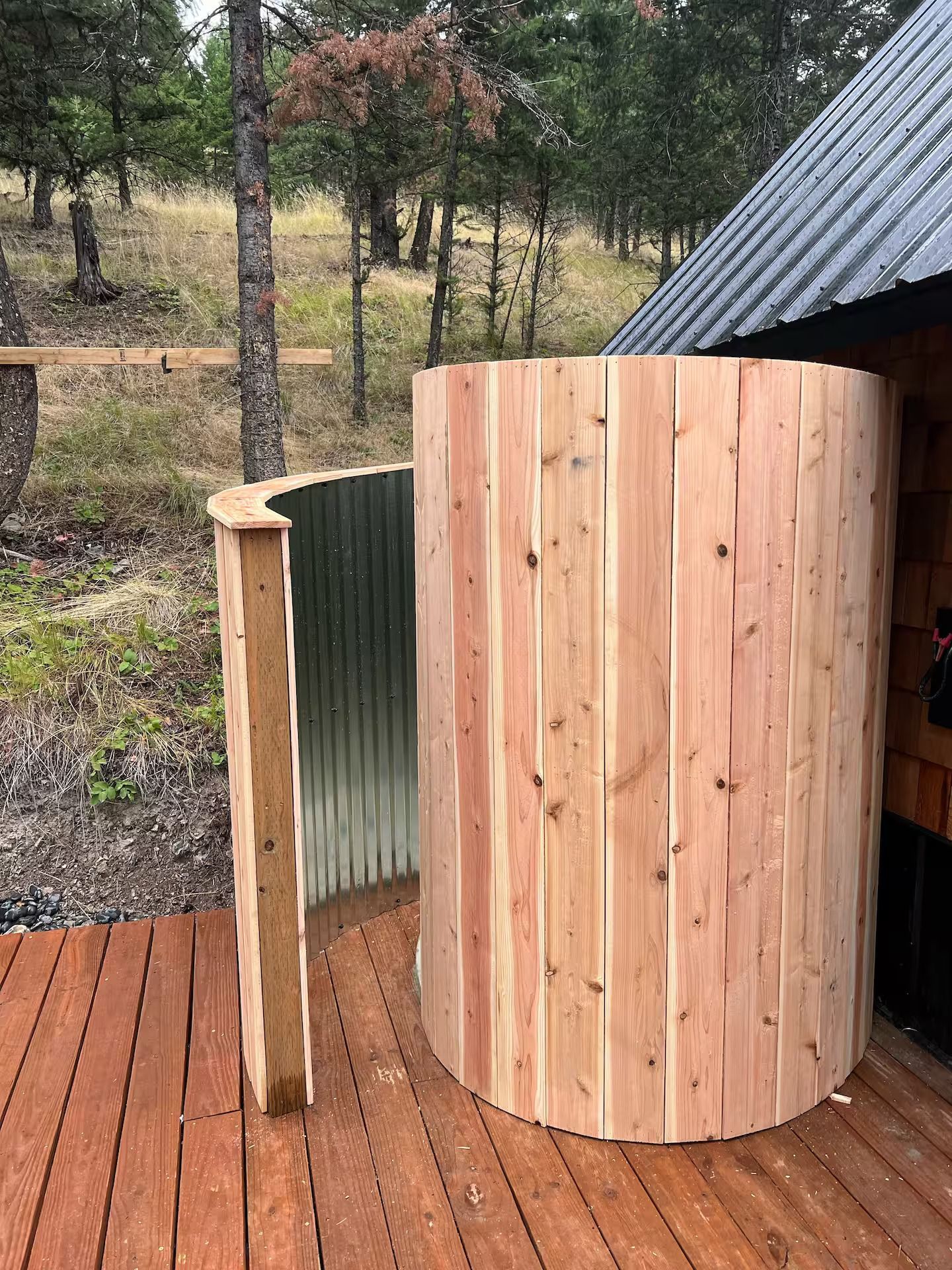 A wooden shower stall is sitting on top of a wooden deck.