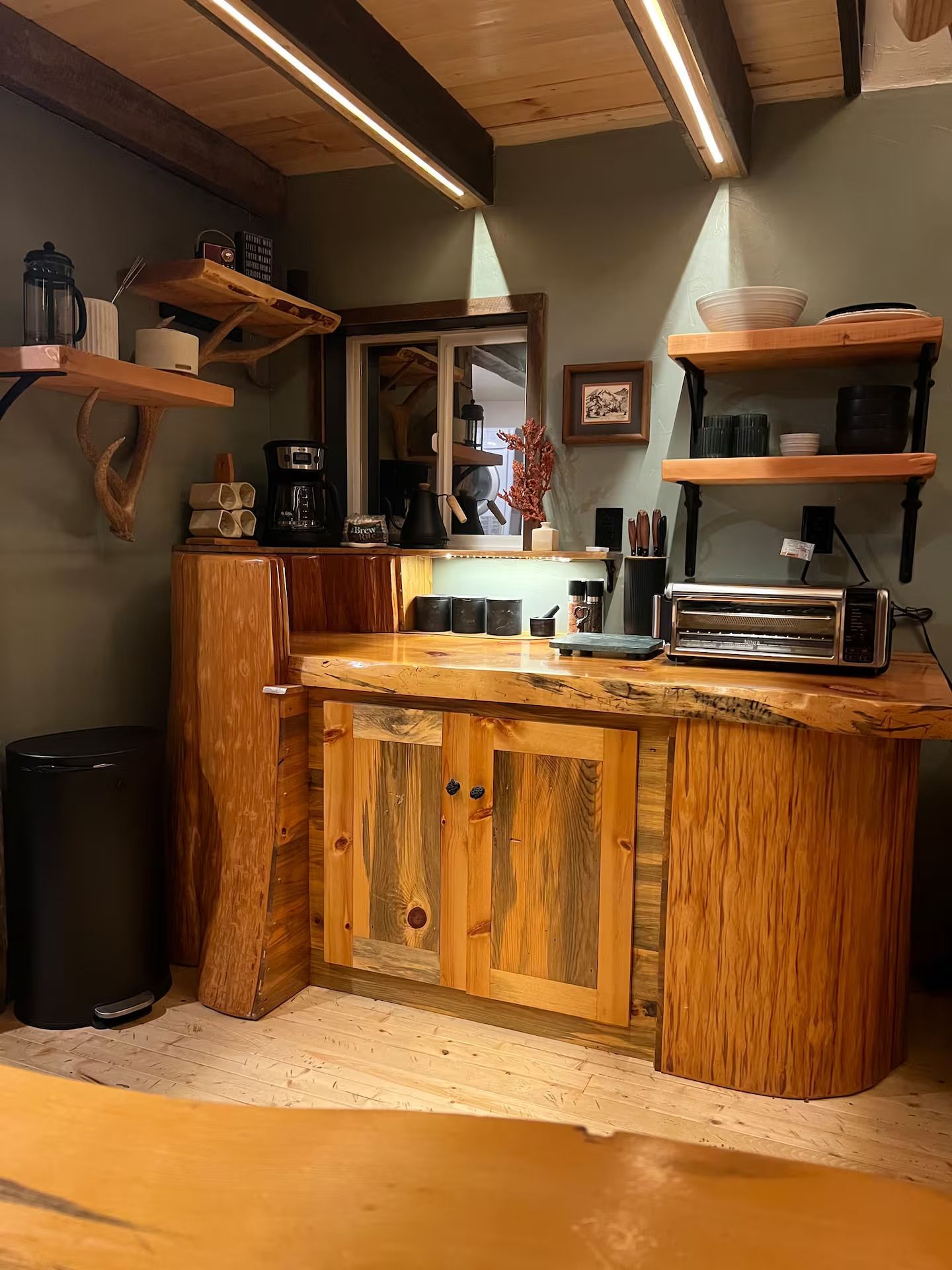 A kitchen with wooden cabinets , shelves , and a toaster oven.
