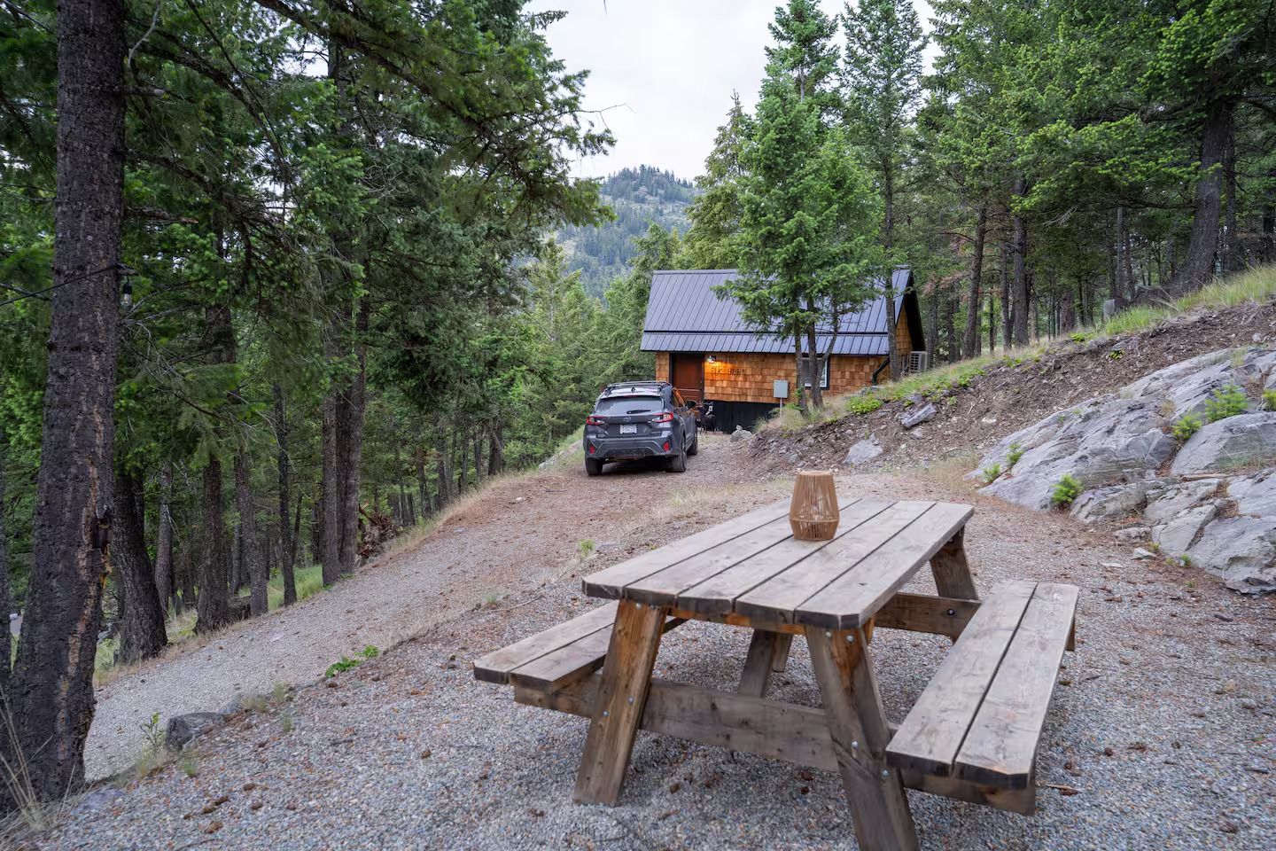 A picnic table is sitting in front of a cabin in the woods.
