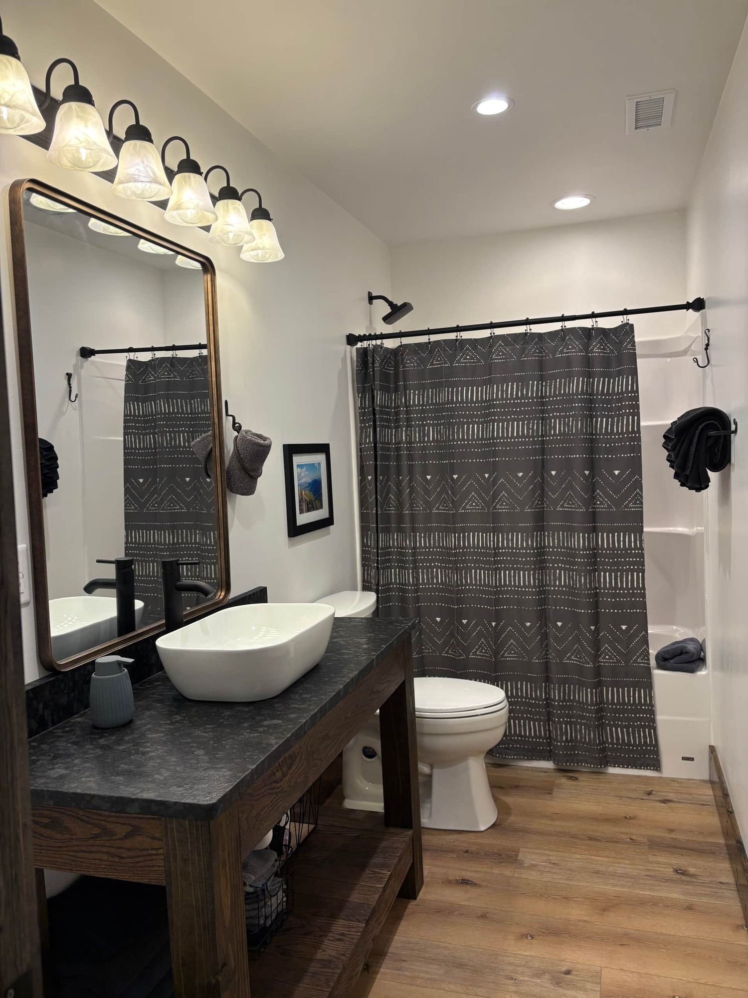 A bathroom with a sink , toilet , shower curtain and mirror.