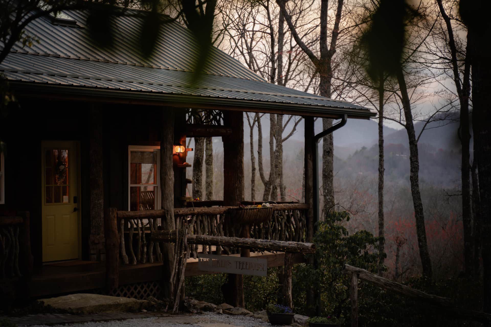 A cabin in the woods with a porch and trees in the background.