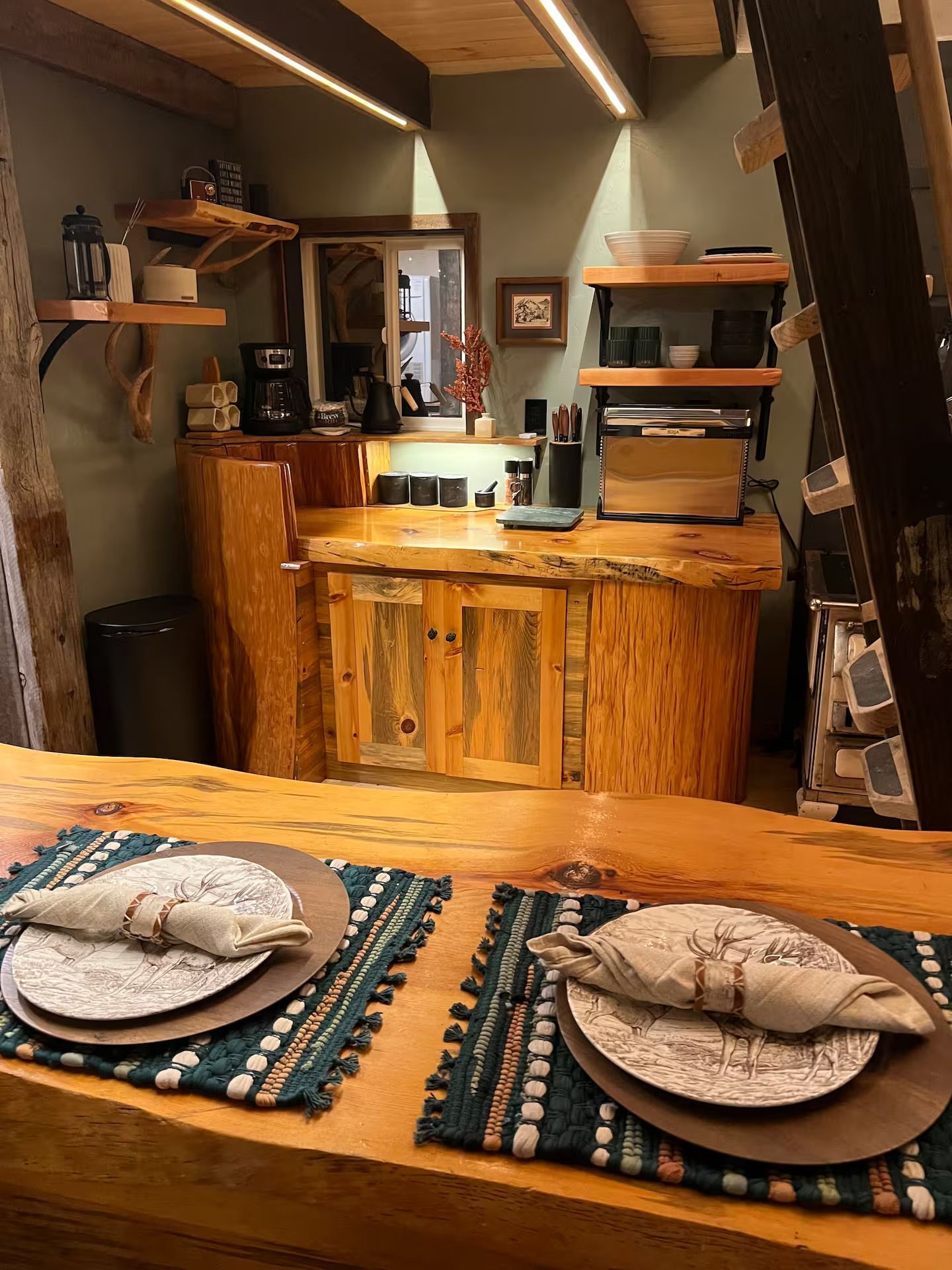 Two plates and napkins are on a wooden table in a kitchen.