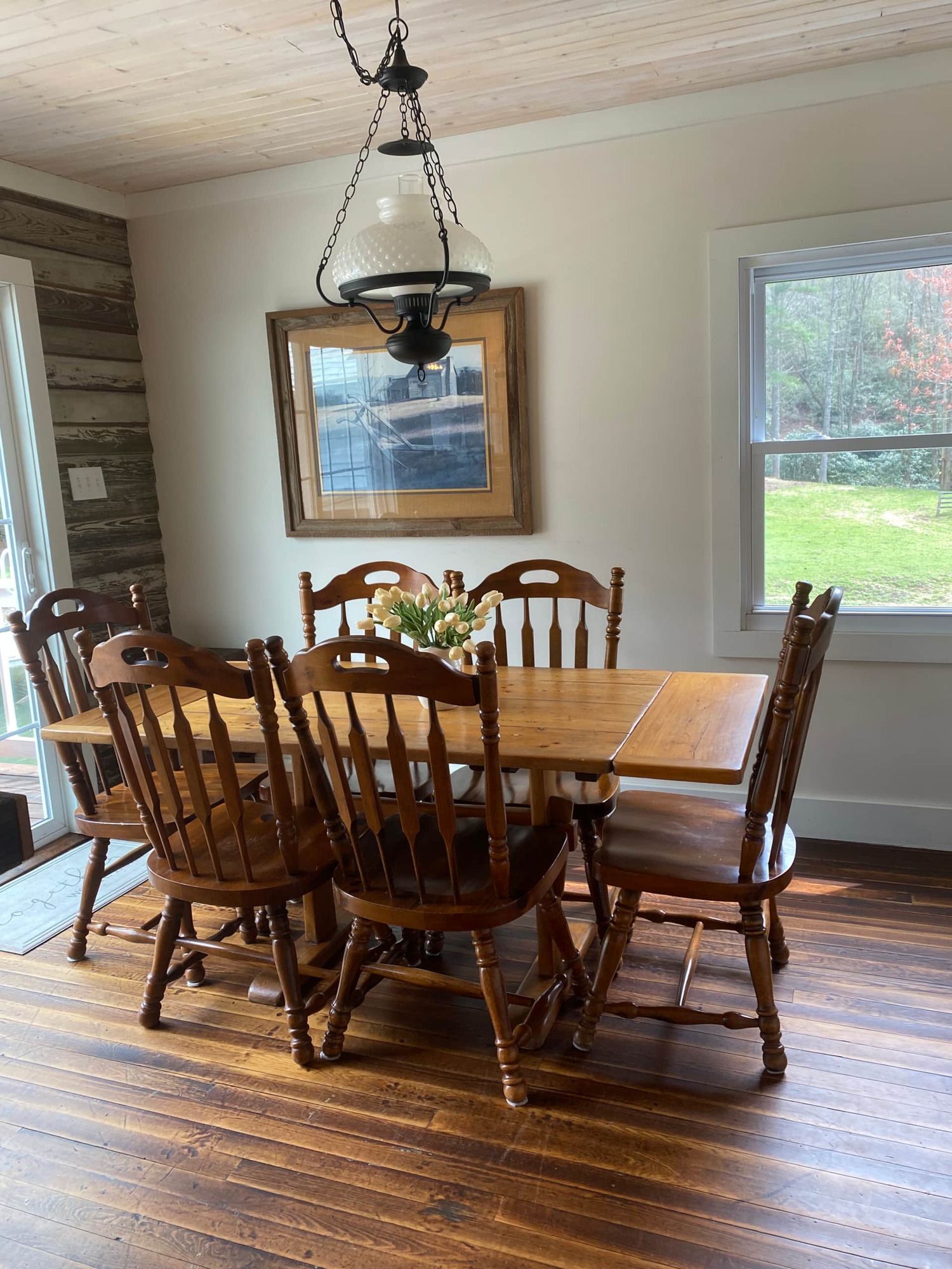 A dining room with a table and chairs and a lamp hanging from the ceiling.