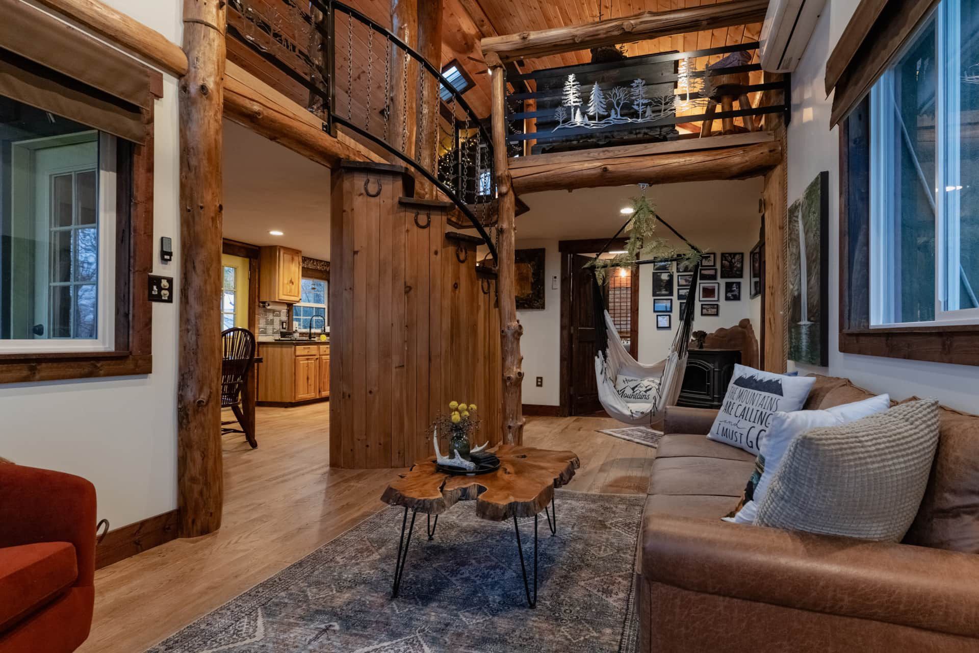 A living room with a couch , table and chairs in a log cabin.