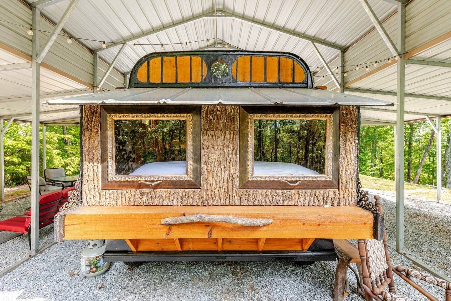 A wooden trailer is parked under a metal roof in a garage.