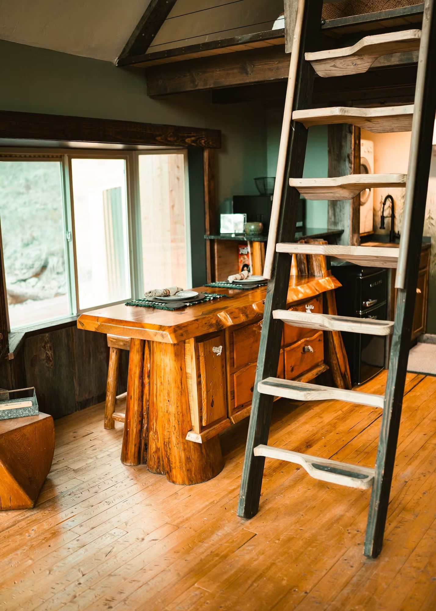 A wooden ladder is leading up to the second floor of a house.