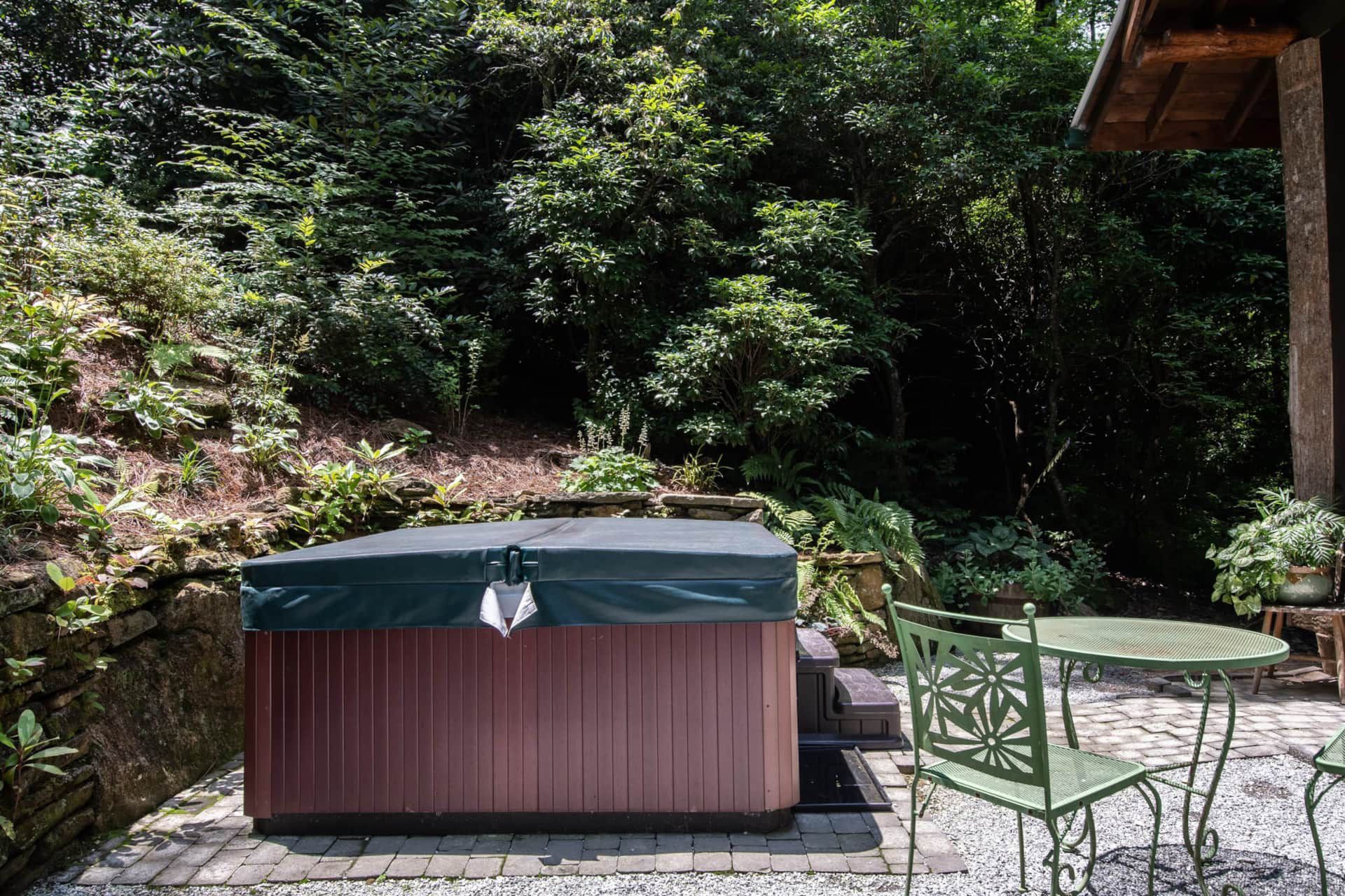 A hot tub is sitting on a patio next to a table and chairs.