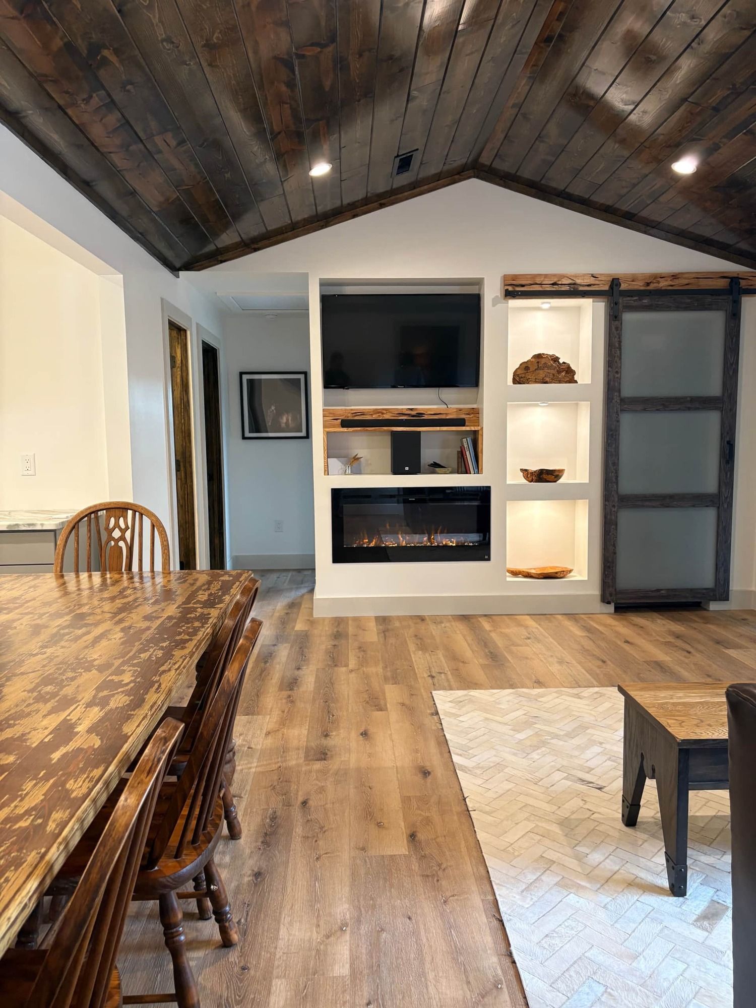 A living room with a wooden table and chairs and a fireplace.