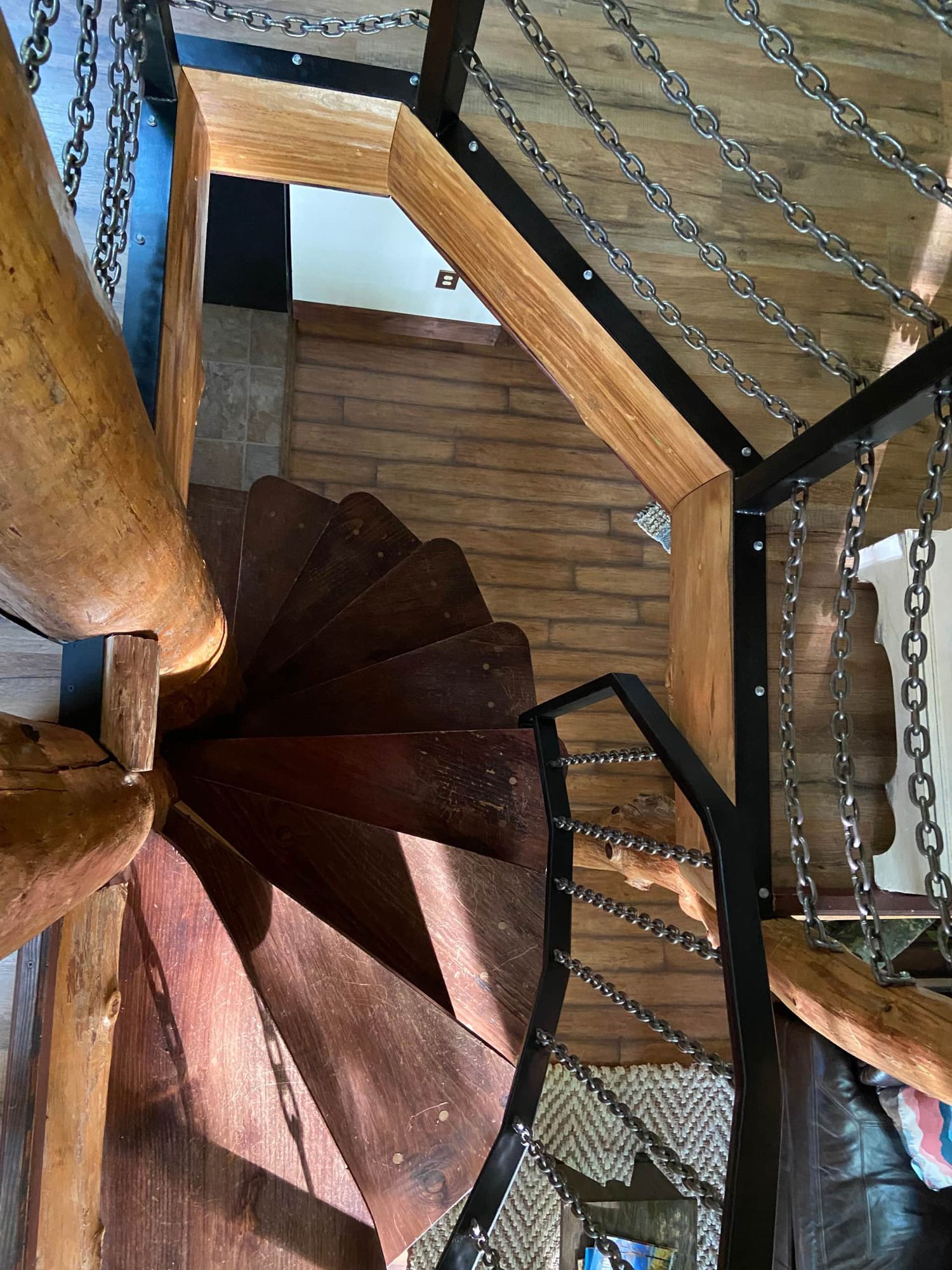 A spiral staircase made of wood and metal with chains.