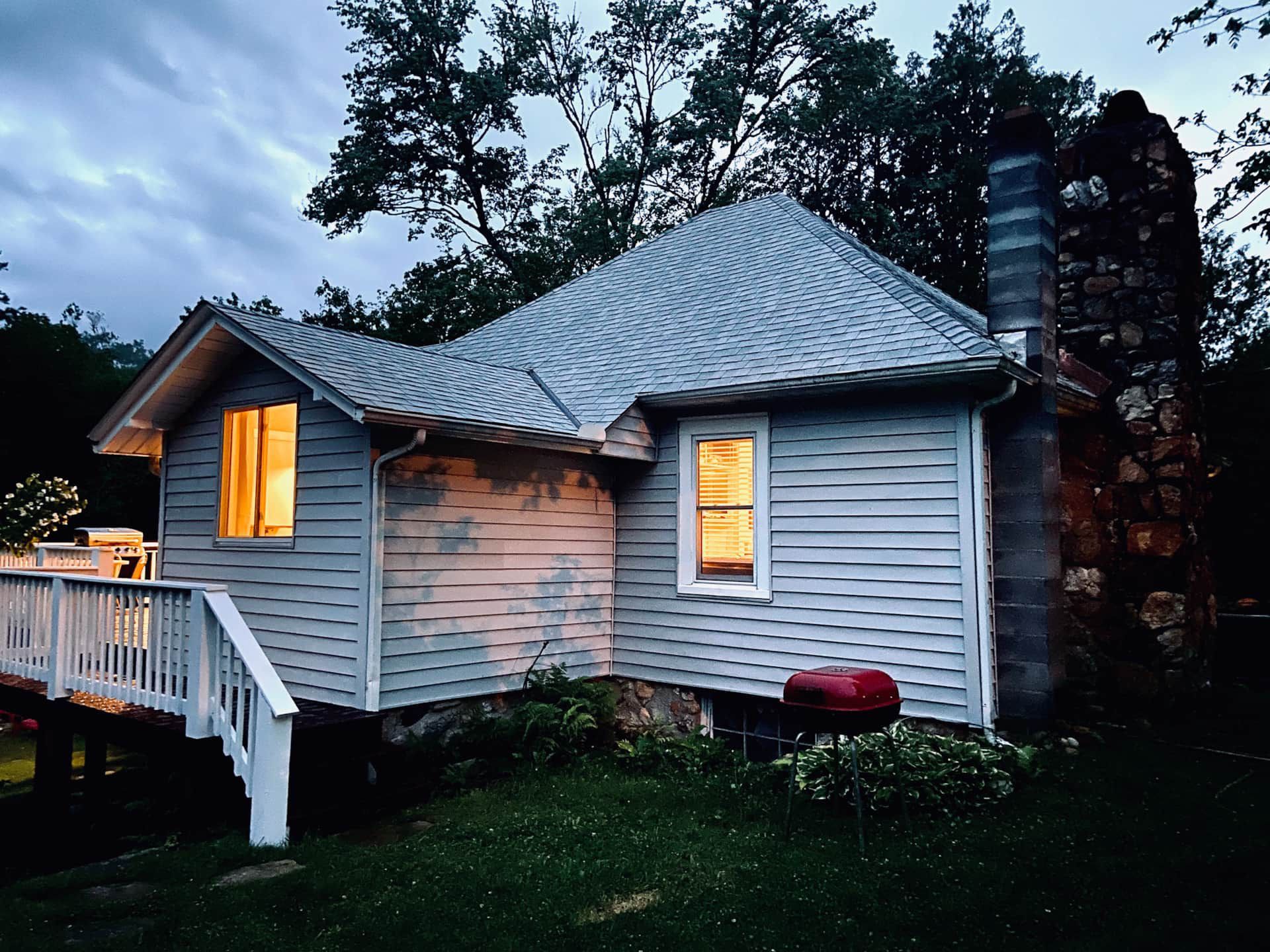 A small white house with a metal roof is lit up at night