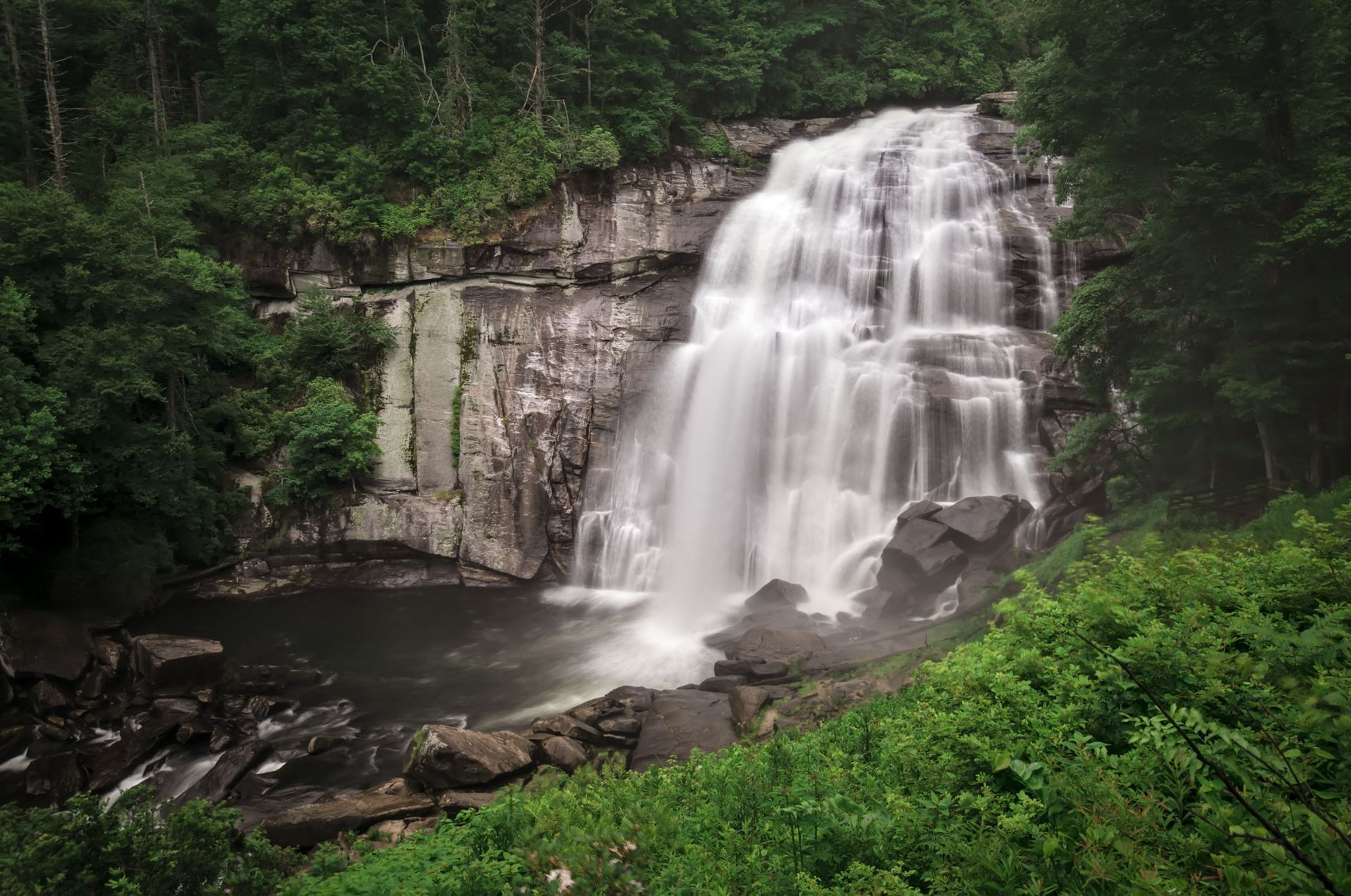 A waterfall in the middle of a canyon with a bridge in the background.