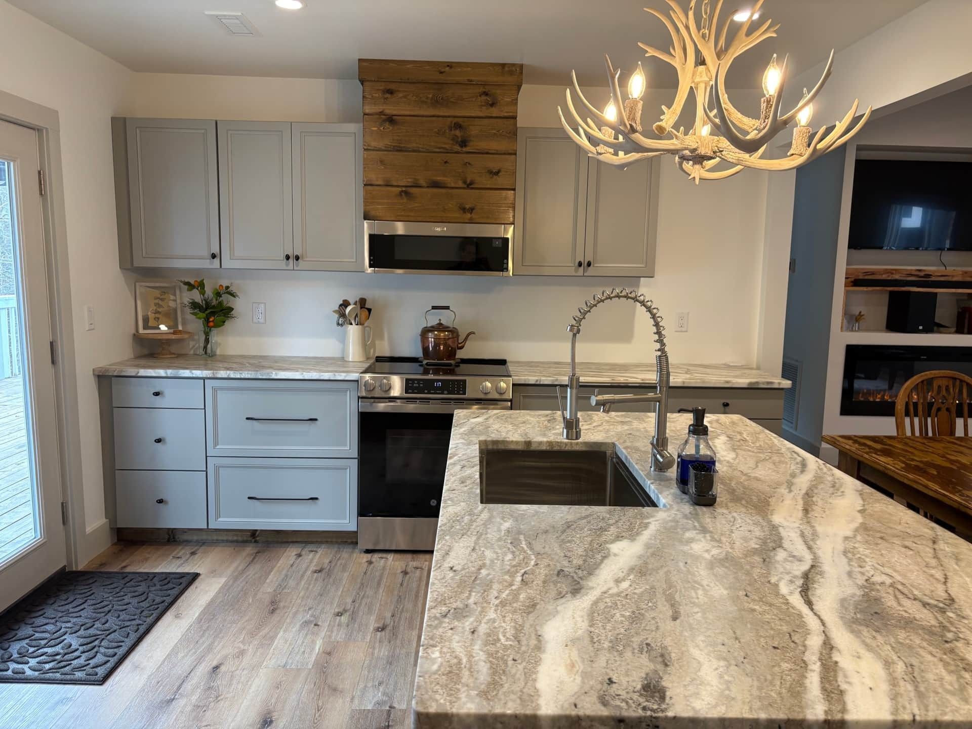 A kitchen with a sink , stove , cabinets and a chandelier.