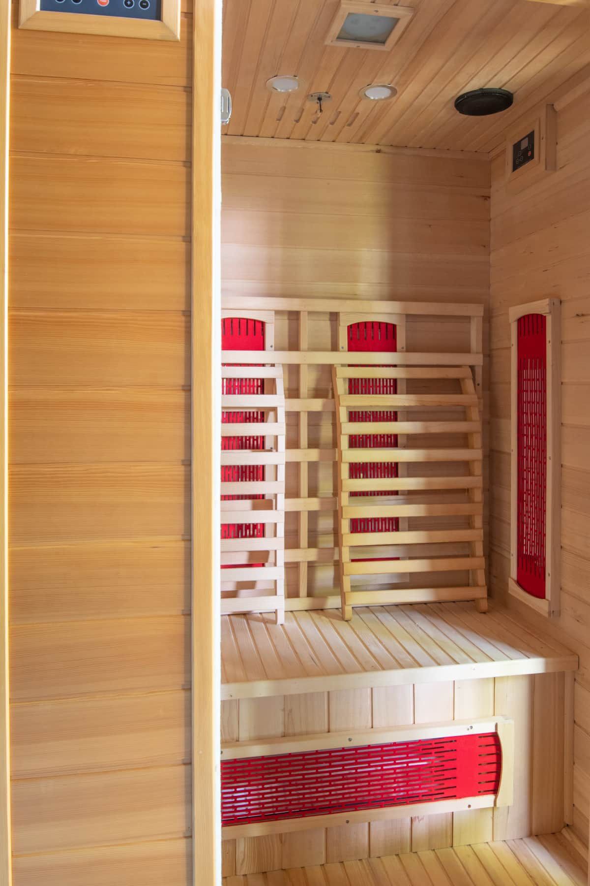 A wooden sauna with red towels and a ladder.