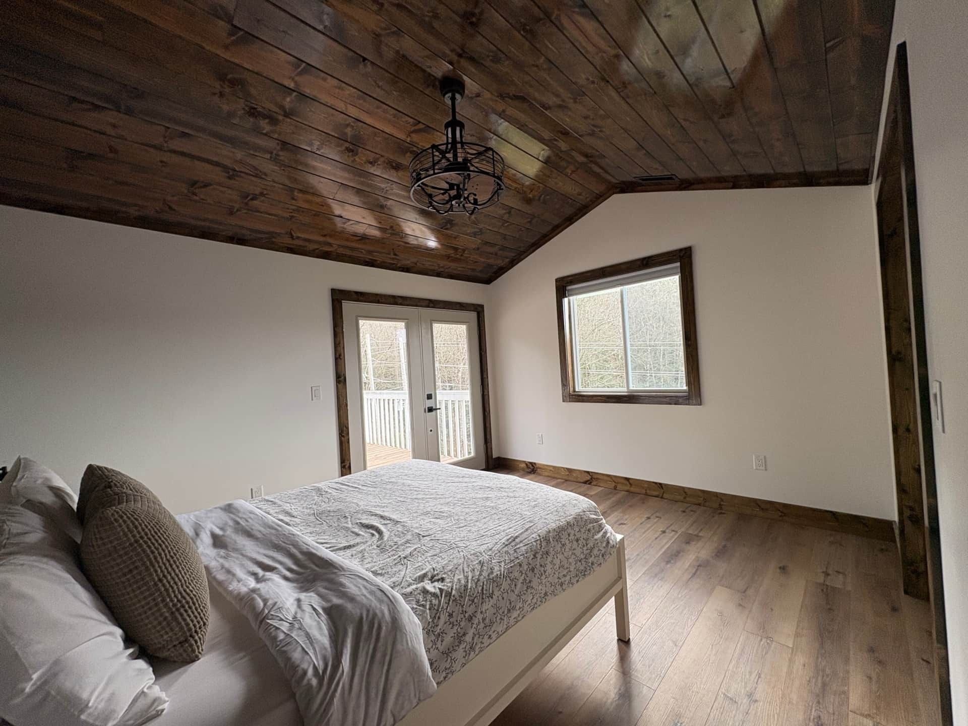 A bedroom with a bed , window and wooden ceiling.