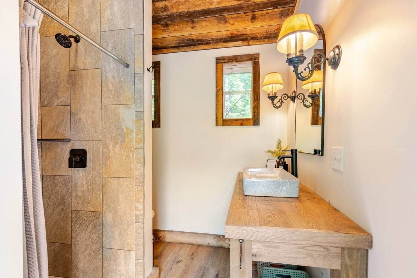 A bathroom with a sink , mirror and shower.
