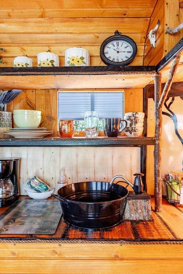 A kitchen with a clock on top of a wooden shelf.