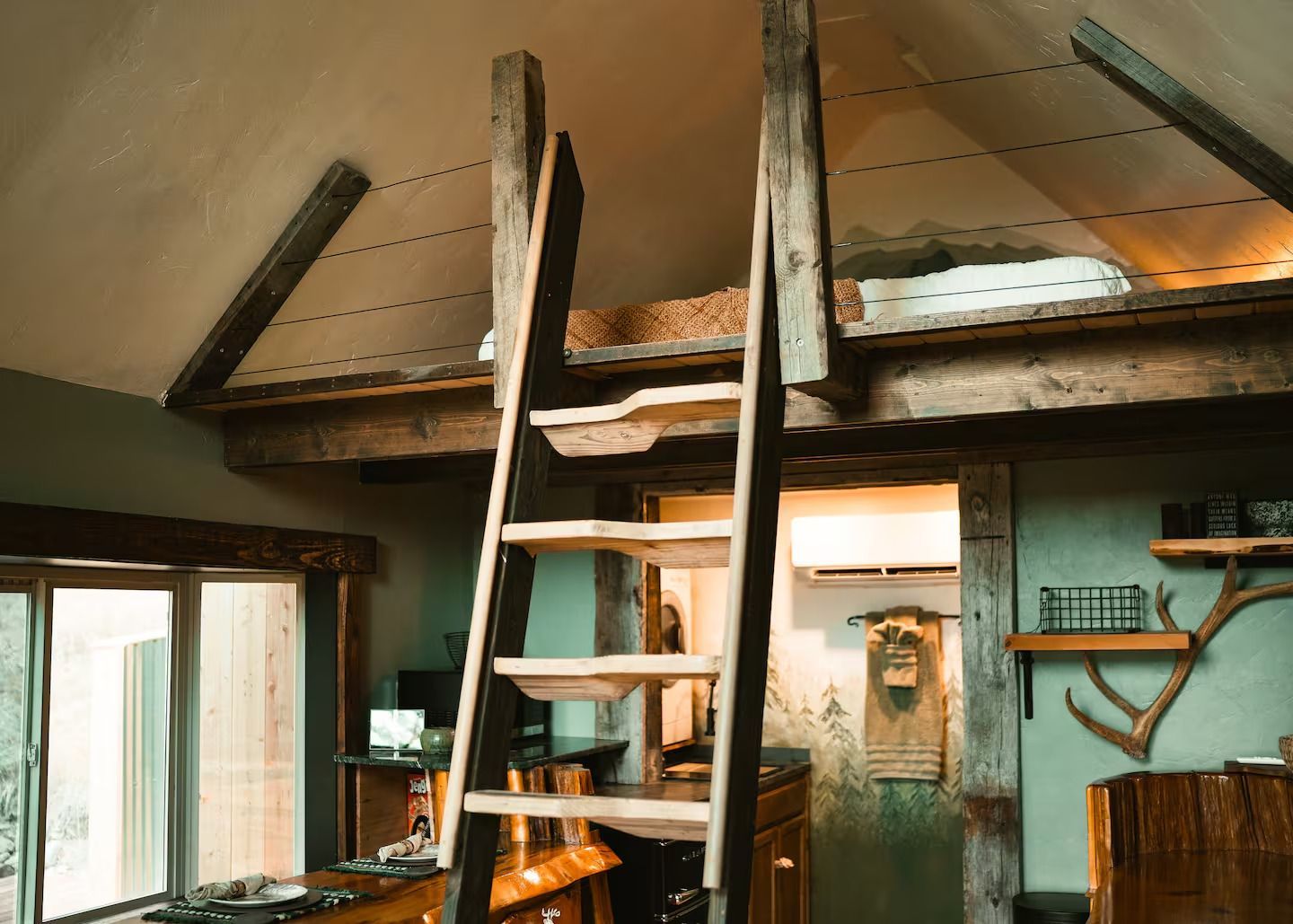 A wooden ladder leading up to a loft bed in a house.