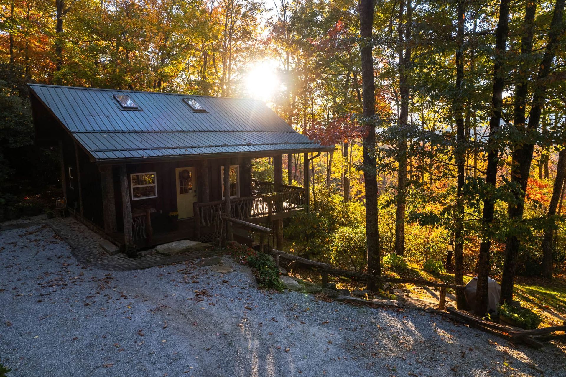 A small cabin in the middle of a forest with the sun shining through the trees.