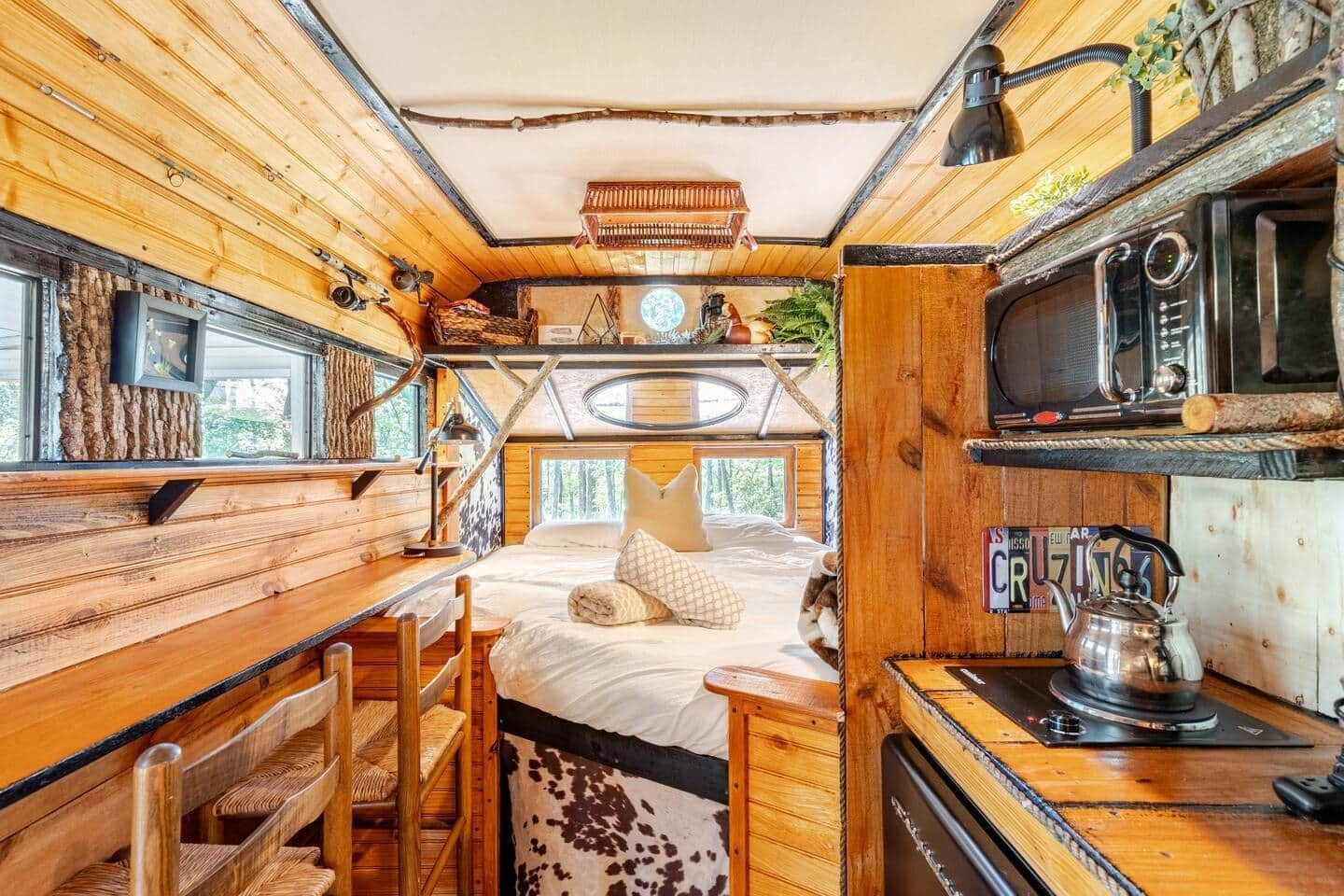The inside of a wooden trailer with a bed and a kitchen.