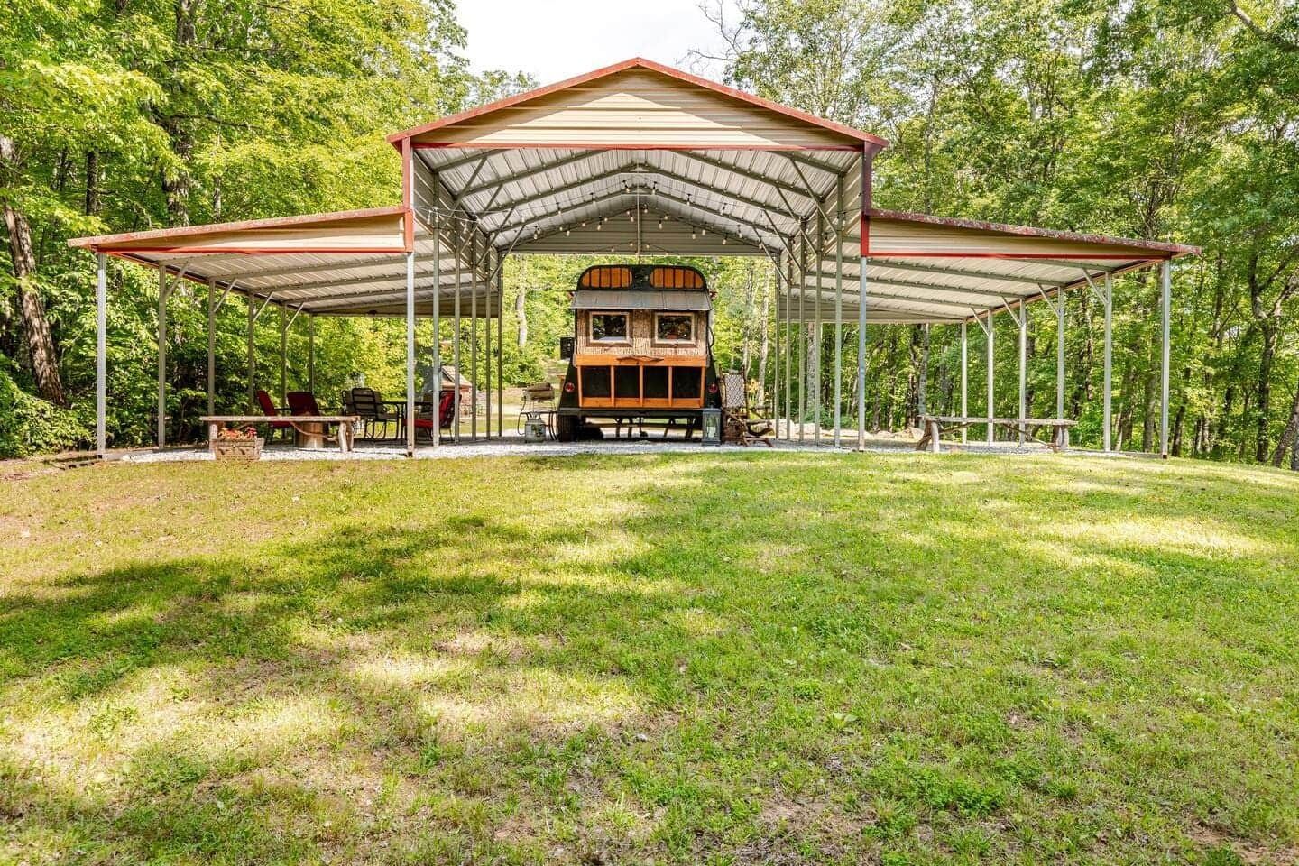 A school bus is parked under a canopy in a grassy field.