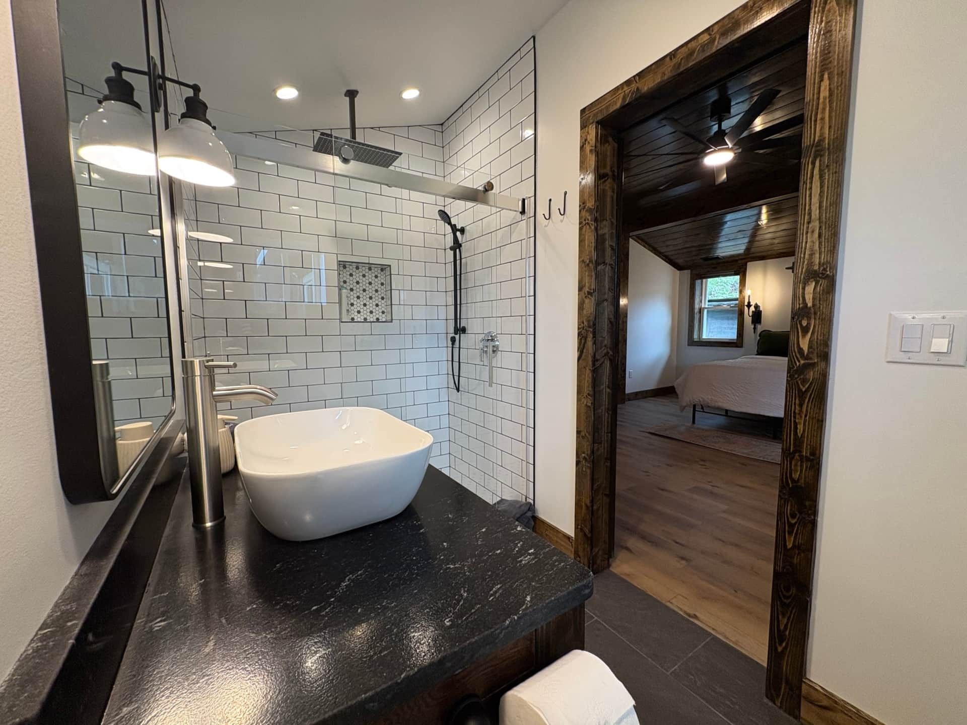 A bathroom with a sink , toilet , mirror and walk in shower.