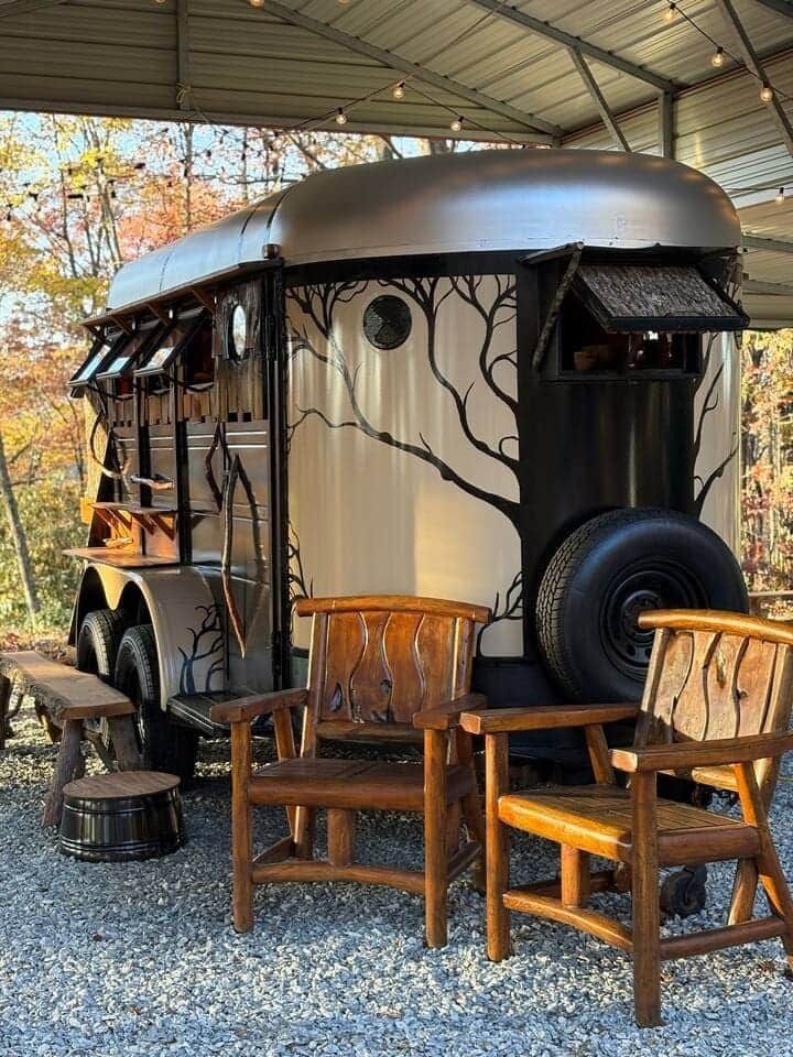 A trailer with wooden chairs and benches parked in front of it.