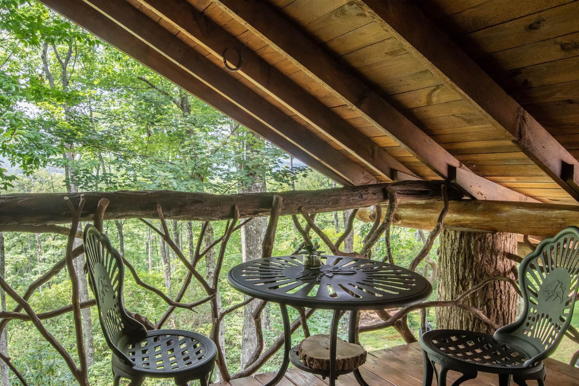 There is a table and chairs on the balcony of a tree house.