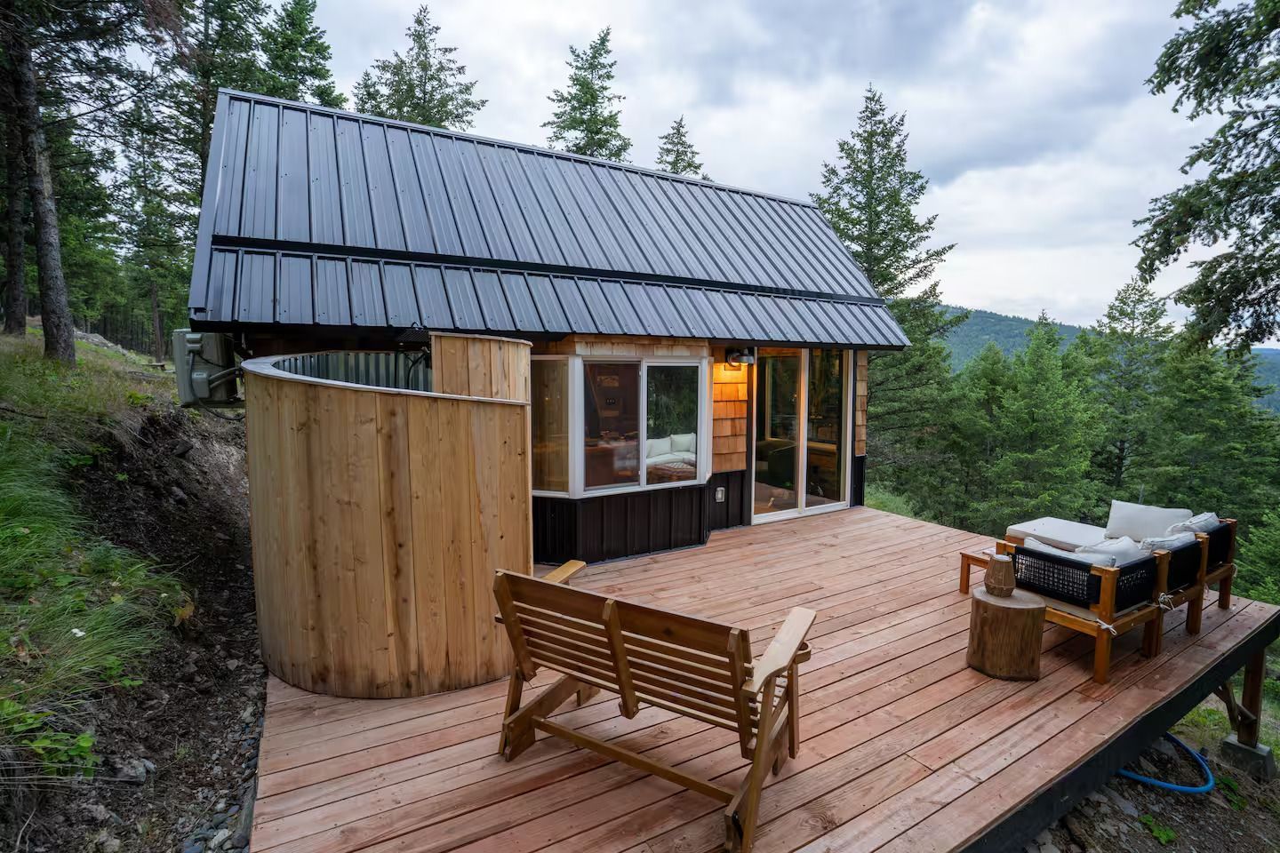 A small house is sitting on top of a wooden deck surrounded by trees.