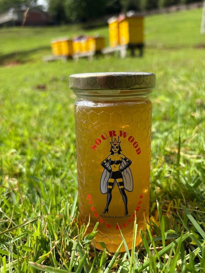 A jar of honey and honeycomb on a wooden cutting board.