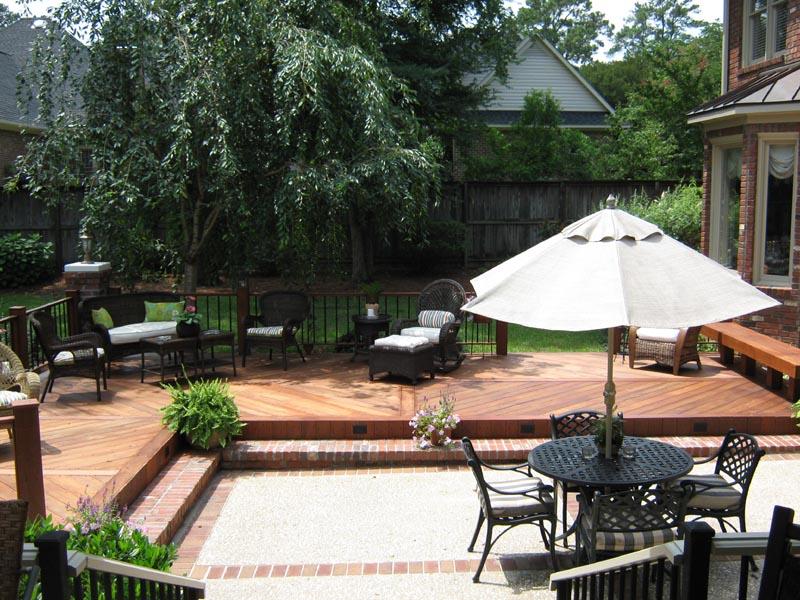 wooden deck surrounding sunken brick and cement patio
