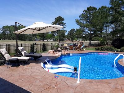 inground pool with chaise lounge chairs and floating pool chairs