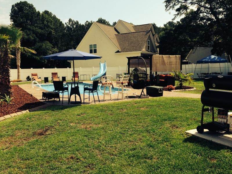 back yard with inground pool slide chairs and patio set