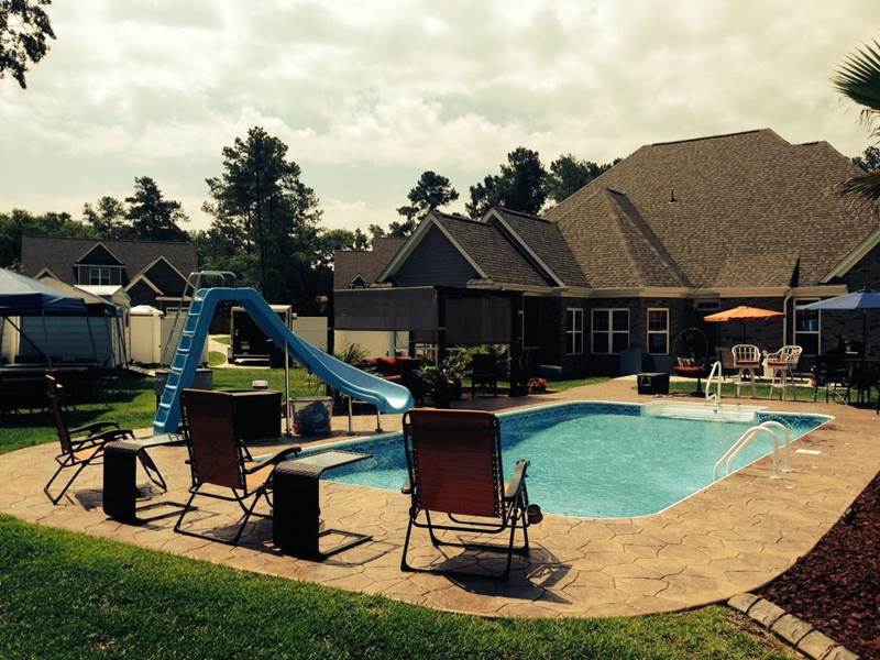 chairs on the decking at end of pool with slide