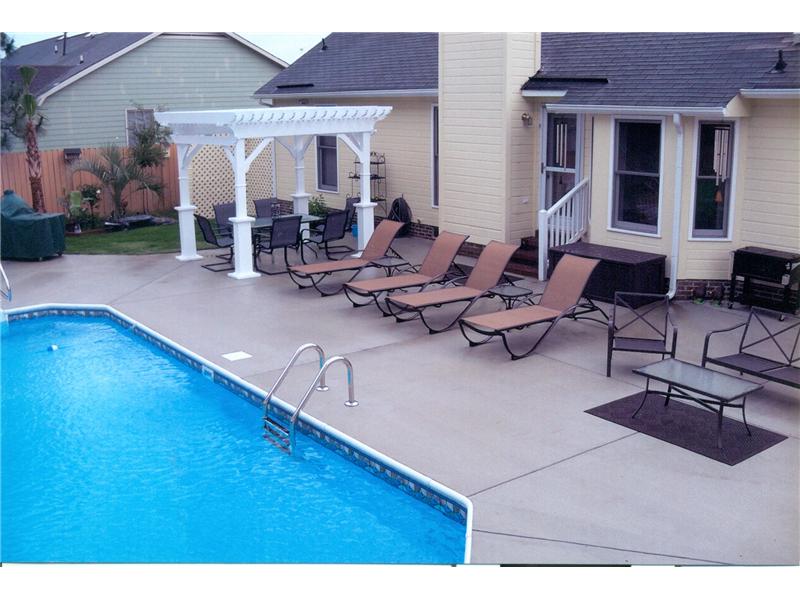 side of inground pool with loung chairs and pergola