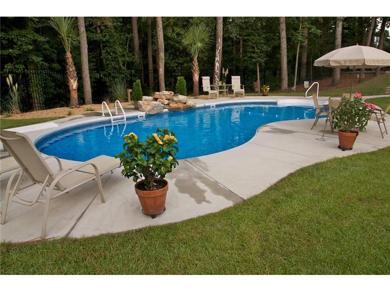 inground pool with patio set potted plants and lounge chairs on decking