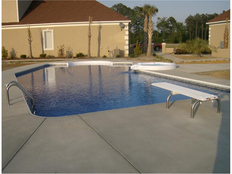 inground pool with diving board and jacuzzi