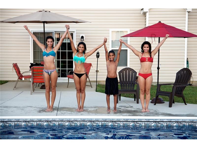 4 kids stading on edge of pool holding hands
