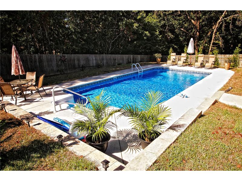 inground pool with patio set lounge chairs and potted plants on decking