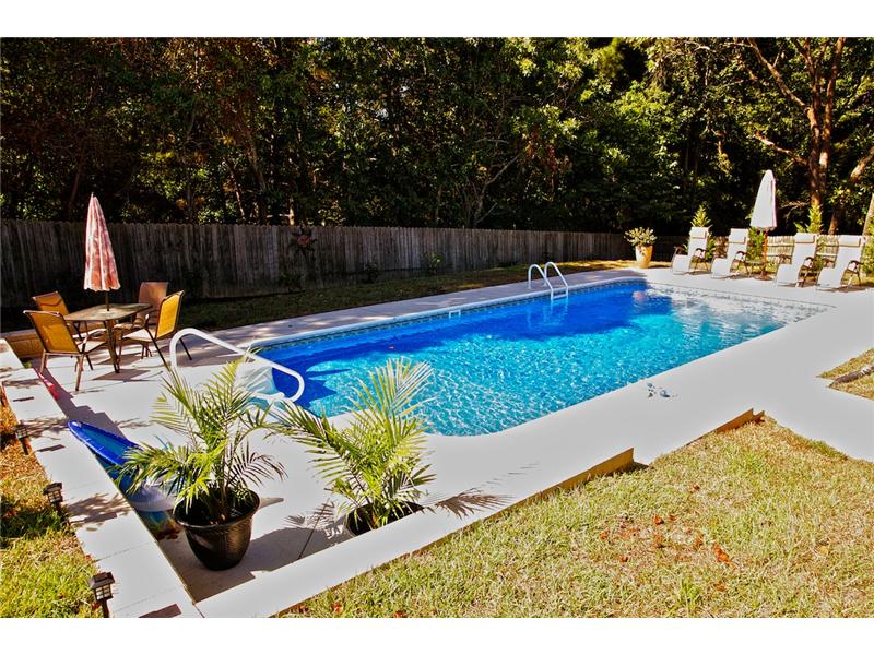 pool with patio set lounge chairs and potted plants on decking